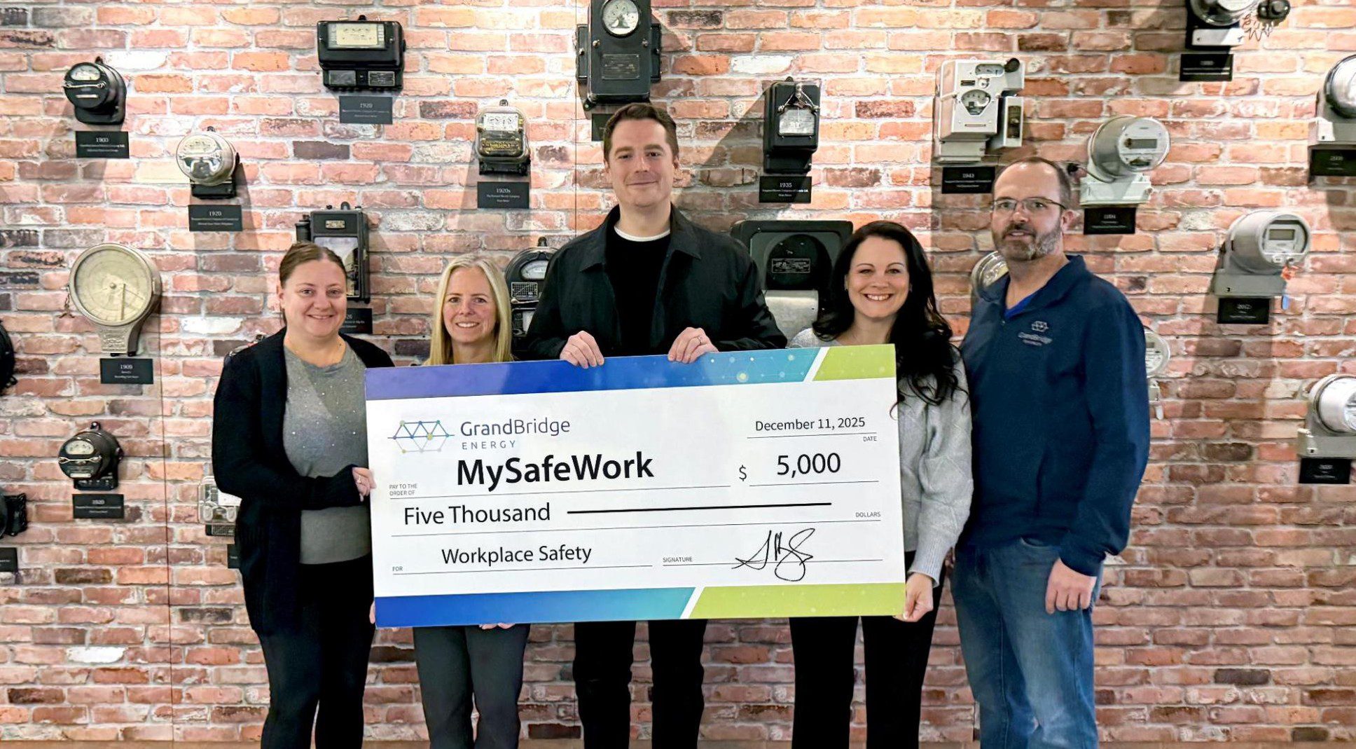 A group of people holding a large cheque for $5000 from MySafeWork