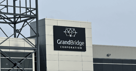 Sign for GrandBridge Corporation on the exterior of a modern commercial building with metal structure nearby.
